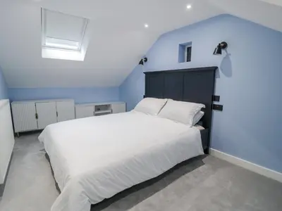 a bedroom with a large white bed with a blue wall at Frongoch Old Power House in Dolgellau