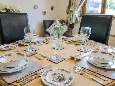 a wooden table with plates and glasses and silverware at Caradoc Cottage in Church Stretton