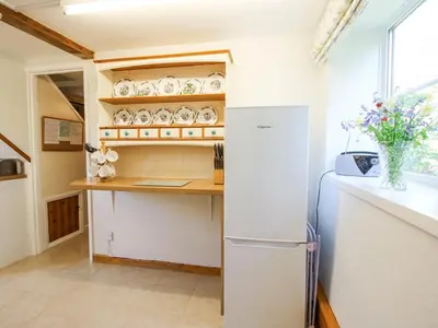 a kitchen with a refrigerator and a shelf with dishes at Caradoc Cottage in Church Stretton