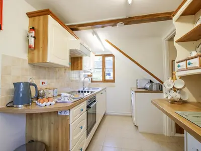 a small kitchen with white cabinets and a sink at Caradoc Cottage in Church Stretton