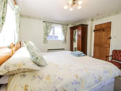 a bedroom with a bed with a floral bedspread at Caradoc Cottage in Church Stretton
