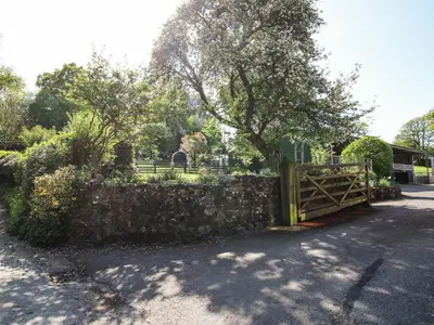 a fence with a wooden gate and a tree at Caradoc Cottage in Church Stretton