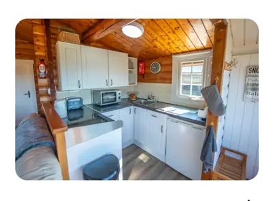a kitchen with white cabinets and a wooden ceiling at Snowdonia Escapes# Scenic Log Cabin with Views, WIFI & 2 Double bedrooms in Trawsfynydd