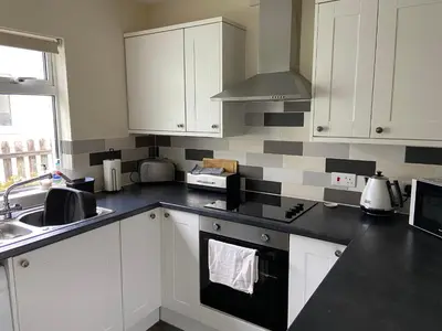 a kitchen with white cabinets and a black counter top at Riverside Bungalow in Llanbedr