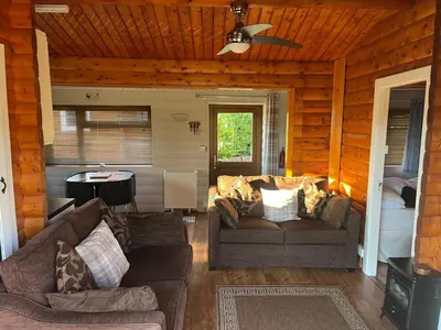 a living room with a couch and a ceiling fan at Home From Home LogCabin in Trawsfynydd