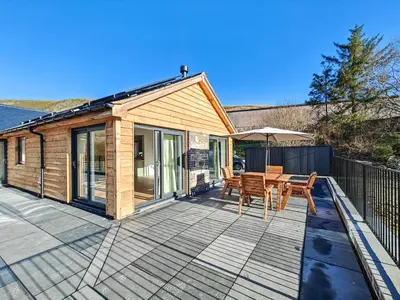 a house with a deck with a table and chairs at 2 Bed in Llanarmon Dyffryn Ceiriog oc-b31110 in Llanarmon Dyffryn-Ceiriog