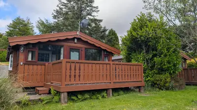 a small cabin with a deck in a yard at Happy Place LogCabin in Trawsfynydd