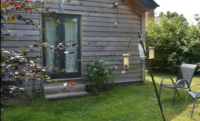 a house with a window and chairs in the yard at Little Hare Lodge - Near Ludlow in Lane to Richards Castle