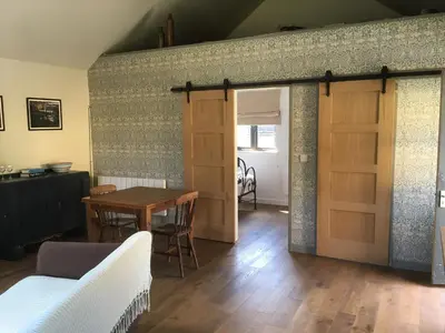 a living room with a wooden door and a table at Little Hare Lodge - Near Ludlow in Lane to Richards Castle