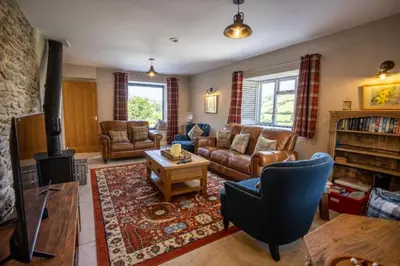 a living room with a couch and a fireplace at Hen Llwyn by Birch Stays New Home in Llangadwaladr