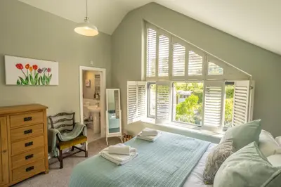 a bedroom with a bed and a dresser and a window at Hen Llwyn by Birch Stays New Home in Llangadwaladr