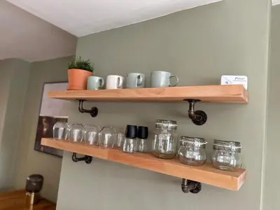 a row of glass jars on wooden shelves on a wall at Bear cottage in Brecon