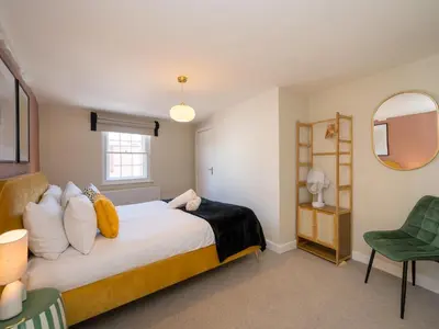 a bedroom with a large bed and a green chair at The Loft - a stylish 2-bed in prime central location - Pass the Keys in Shrewsbury