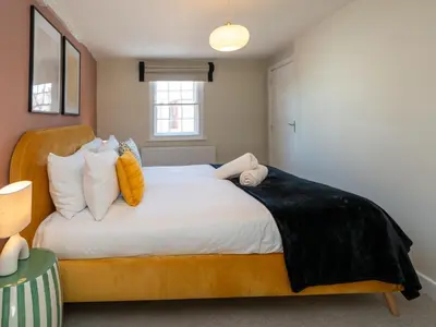 a bedroom with a large bed with yellow and white pillows at The Loft - a stylish 2-bed in prime central location - Pass the Keys in Shrewsbury
