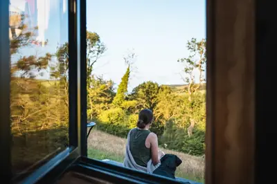 a woman sitting with a dog looking out a window at Hydra in Llangollen