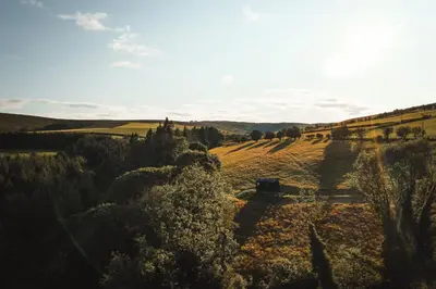 an aerial view of a field with a barn in the distance at Hydra in Llangollen