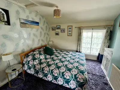 a bedroom with a bed with a green comforter and a window at Severn Up in Newtown