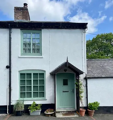 a white house with a green door and windows at Severn Up in Newtown