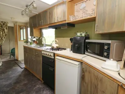 a kitchen with a stove and a microwave at Gwybedog in Llanwrda