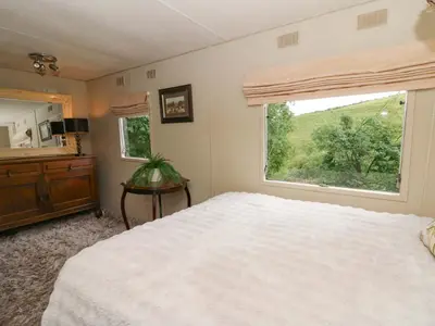 a bedroom with a large white bed and a window at Gwybedog in Llanwrda
