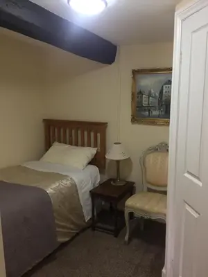 a bedroom with a bed and a chair and a lamp at Borderers Inn in Brecon