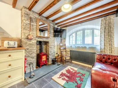 a living room with a red couch and a stone fireplace at Coach House - Uk49793 in Cribyn