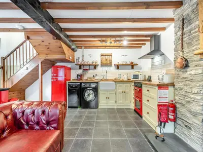 a kitchen with a couch and a washer and dryer at Coach House - Uk49793 in Cribyn