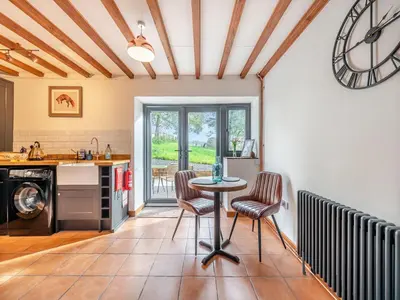 a kitchen with a table and chairs and a clock at Sheep Shed - Uk49794 in Cribyn