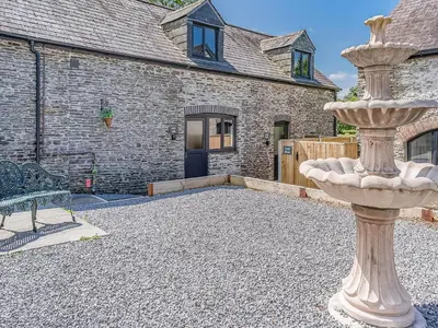 a stone house with a stone fountain in the yard at Sheep Shed - Uk49794 in Cribyn