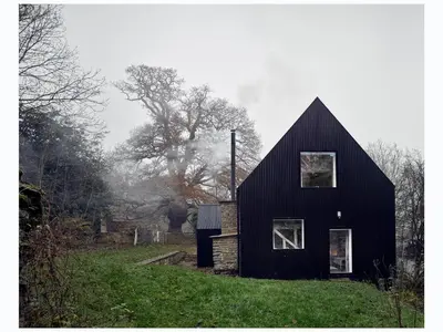 a black house sitting on top of a lush green field at Croft Lodge Studio in Leominster