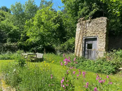 a stone building with a bench in a garden at Croft Lodge Studio in Leominster