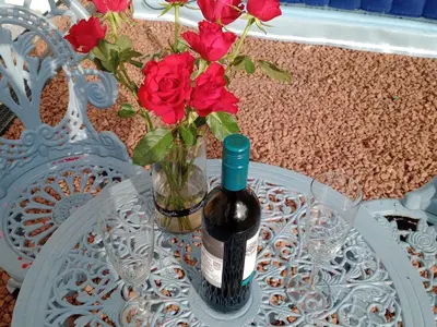 a bottle of wine and a vase of roses on a table at Chandler Ranch Llandovery Cynghordy in Cynghordy