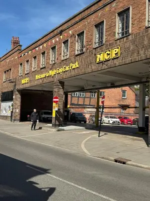 a man walking under a bridge over a street at English Bridge Court in Shrewsbury