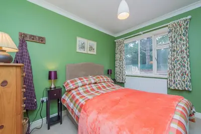 a green bedroom with a bed and a window at Pear Tree Cottage in Shrewsbury