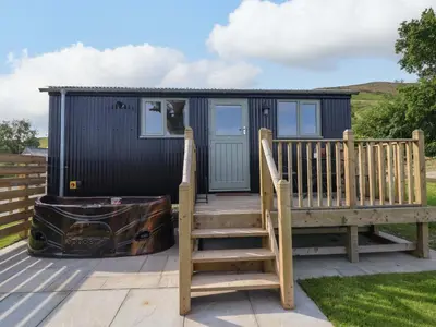 a black tiny house with a staircase and a bench at Cheviot in Oswestry