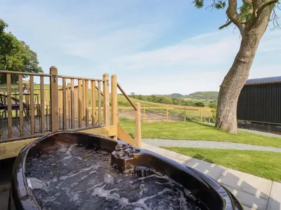 a hot tub in a backyard with a tree at Cheviot in Oswestry