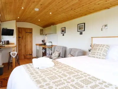 a bedroom with a large white bed and a kitchen at Defaid Cymreig in Oswestry