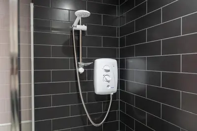 a shower in a black tiled bathroom at Mermaids Hideaway in Aberaeron
