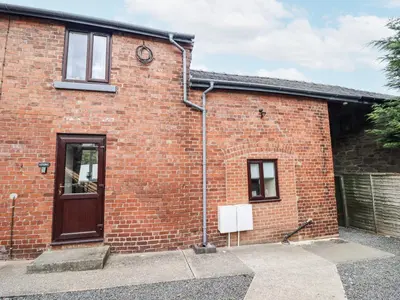a brick building with a door and a window at 1 Y Llew in Llandinam