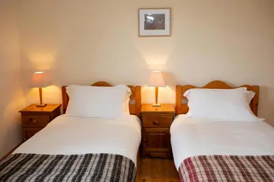 two beds in a room with two lamps on night stands at Owls Roost Eco Lodge Apartment Lampeter in Lampeter