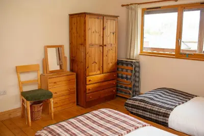 a bedroom with a bed and a cabinet and a chair at Owls Roost Eco Lodge Apartment Lampeter in Lampeter
