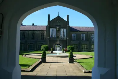 an archway leading to a large building with a fountain at Owls Roost Eco Lodge Apartment Lampeter in Lampeter