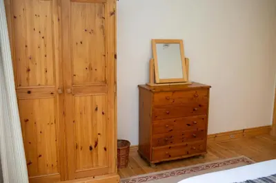 a bedroom with a wooden cabinet and a mirror on a dresser at Robins Perch Eco Lodge Apartment Lampeter in Lampeter