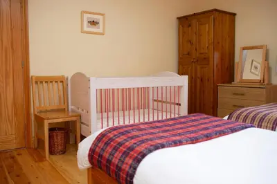 a bedroom with a crib and a dresser and a bed at Robins Perch Eco Lodge Apartment Lampeter in Lampeter