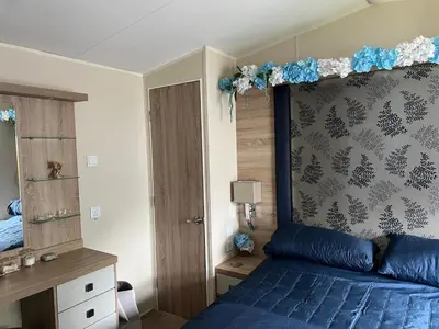 a bedroom with a blue bed with a floral headboard at Sher, My Happy super static -2026 Award winner in Llanddwywe