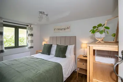 a bedroom with a bed and a desk and window at Birch Banc Retreats - Bedw Cabin