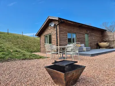 a table and chairs in front of a log cabin at Birch Banc Retreats - Bedw Cabin