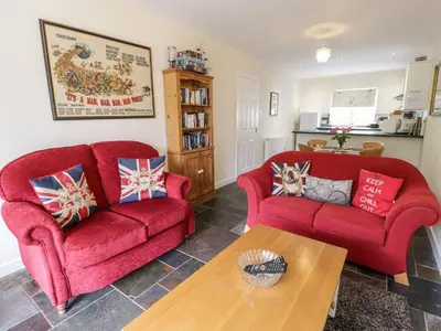 a living room with two red couches and a table at 3 Riverside Bungalows in Llanbedr