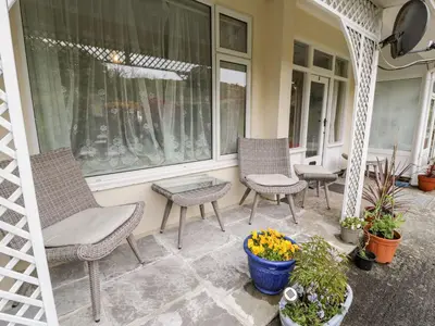 a porch with chairs and a table and flowers at 3 Riverside Bungalows in Llanbedr