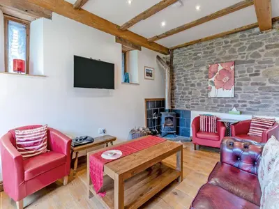 a living room with red furniture and a tv at Wern Farm Barn in Cwmdu